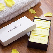 Box of yellow soaps with yellow petals and white towel.