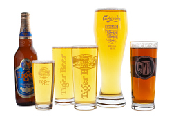 Five filled branded beer glases alongside a bottle of Tiger lager.