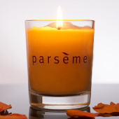 Parseme Candle on reflective surface with petals.